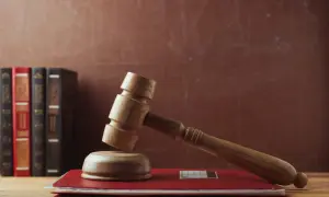 Martelletto da giudice su un libro rosso, con libri legali sullo sfondo. Rappresenta il **significato** di interdizione e giustizia.