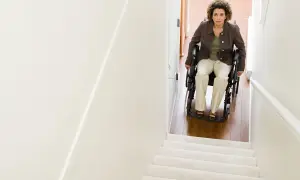 Donna in carrozzina guarda verso l'alto, pronta per il trasporto disabile su per le scale.