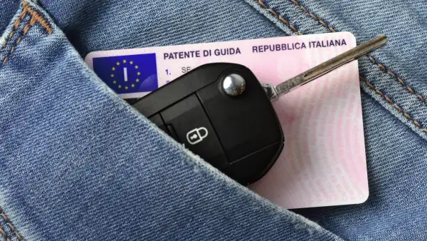 Patente di guida italiana e chiavi dell'auto in un taschino di jeans, pronti per il rinnovo patente.